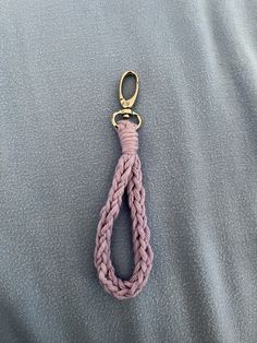 a pink rope with a gold hook hanging from it's end on a gray surface