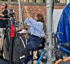 a woman sitting on top of a bike next to a man holding a cell phone