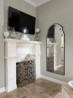 a living room with a fireplace, mirror and television on top of the mantel