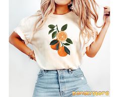 Bring a slice of summer to your wardrobe with our Boho Oranges Tshirt! 🍊🧡 Printed on trendy and loved by many Comfort Colors tshirts, this vibrant orange fruit shirt is perfect for embracing the boho cottagecore vibe. The hand-drawn vintage graphic of a branch with lush green leaves and juicy oranges adds a cute and summer inspired touch. Whether you're a fan of citrus or looking for a unique gift for her, this shirt is sure to brighten up your day! 🎁 #OrangesAreLife #FruitFashionStatement 🍊 Orange Summer Shirt With Screen Print, Orange Crew Neck Shirt For Summer, Fruit Shirt, Summer Orange, Buy Clothes Online, Boho Cottagecore, Orange Fruit, Vintage Graphic, Unique Gifts For Her