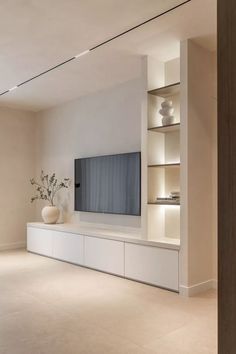 an empty living room with a large flat screen tv on the wall and shelves in front of it