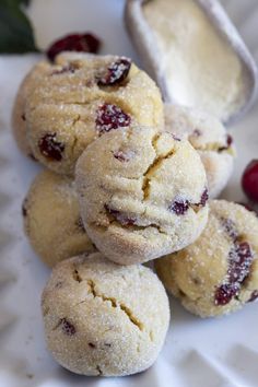 several cranberry cookies on a white plate with some cranberries in the background