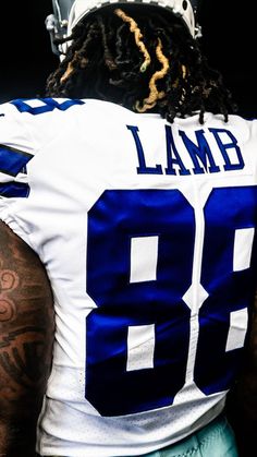 a football player with dreadlocks on his head wearing a white and blue uniform