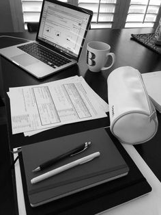 an open laptop computer sitting on top of a desk next to a notebook and pen