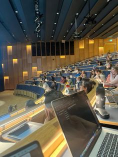 people are sitting in an auditorium with laptops