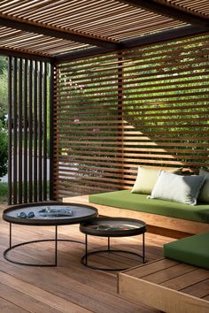 an outdoor living area with wooden slatted walls and green cushions on the couches