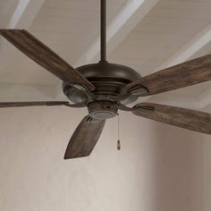 a ceiling fan with wooden blades in a room