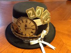 a hat with a clock and ribbon around it sitting on a wooden table next to a pair of scissors