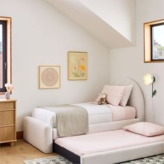 two twin beds in a bedroom with white walls and wooden flooring, framed pictures on the wall