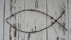 barbed wire is attached to the side of an old white wooden wall with peeling paint