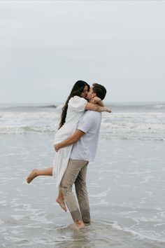 a man and woman hug while standing in the ocean