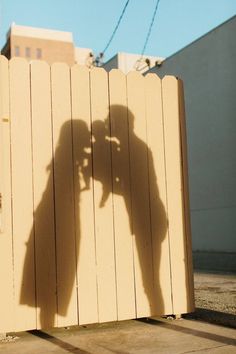 the shadow of a person standing in front of a wooden fence