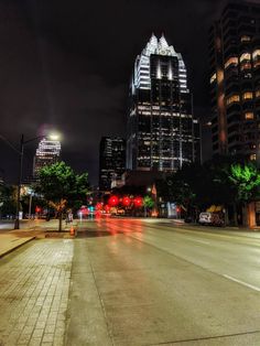 an empty city street at night with tall buildings in the background