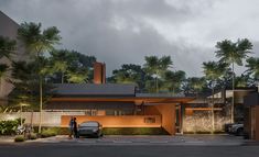 an artist's rendering of a modern house in the evening with two cars parked outside