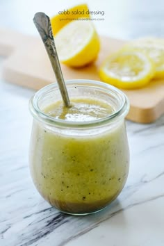 a glass jar filled with green liquid next to sliced lemons