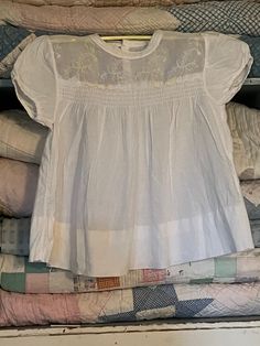 "This adorable vintage baby dress is white cotton with sweet yellow embroidered flowers. There's smocking on the front and measures approximately 12\" from the shoulders to the hem. There's no tag but I would say it would fit 12 months? It has been washed and ironed and has a button closure on the back with no stains or tears." Vintage Smocked Bodice Top For Summer, Vintage Summer Tops With Smocked Bodice, White Cotton Blouse With Smocked Bodice, Cotton Tops For Baptism In Spring, White Smocked Short Sleeve Blouse, Fitted Top For Baptism In Spring, Fitted Tops For Baptism In Spring, Cotton Baby Dress, Vintage Baby Dress