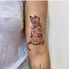 a woman's arm with flowers and the letter l tattooed on her left arm