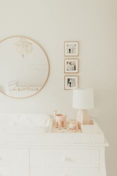 a baby crib in front of a mirror and pictures on the wall above it