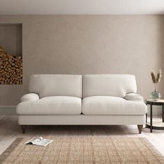 a white couch sitting on top of a hard wood floor next to a wooden table