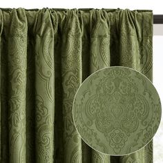 the green curtains are hanging in front of a window with an ornate design on it