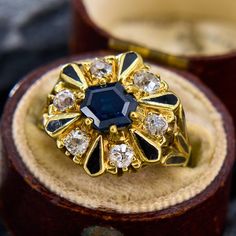 an antique ring with blue stone surrounded by white and clear stones in a wooden box