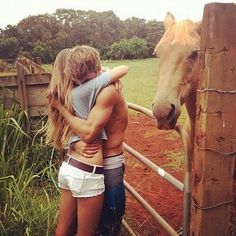 a man and woman hugging in front of a horse