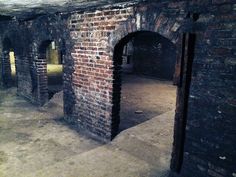 an old brick building with arched doorways in the center and light coming from it