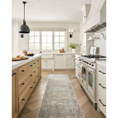 a kitchen with white cabinets and an area rug on the floor in front of the stove