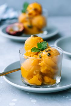 two small bowls filled with fruit on top of a white tablecloth and silverware