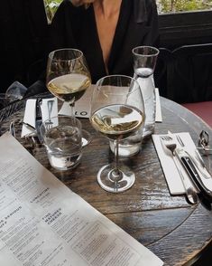 a woman sitting at a table with two glasses of wine