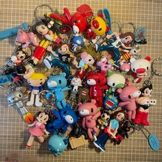 a bunch of key chains that are laying on a table together with some cartoon figures