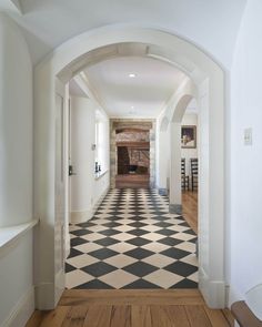 an arched hallway leading to a living room and dining area with black and white checkered flooring