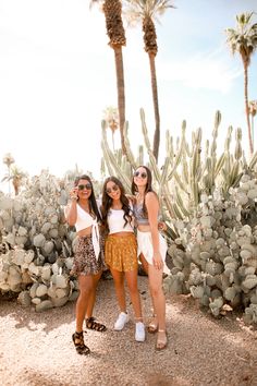 two girls standing next to each other in front of cacti and cactus trees