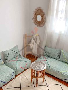 a living room filled with green couches next to a white rug on top of a hard wood floor