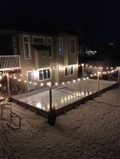 an ice rink with lights on it in front of a house at night, surrounded by lawn chairs