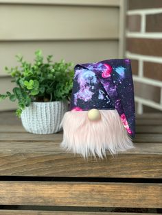 a purple and black hat with white fur on top of a wooden table next to a potted plant