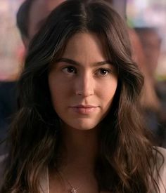 a close up of a person with long hair wearing a white shirt and pink flowered top