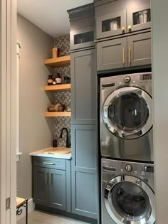 a washer and dryer in a small room with shelves on the wall behind them