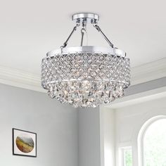 a crystal chandelier hanging from the ceiling in a room with white walls and windows