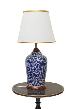 a blue and white vase sitting on top of a table next to a lampshade