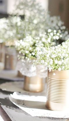 some white flowers are in vases on a table