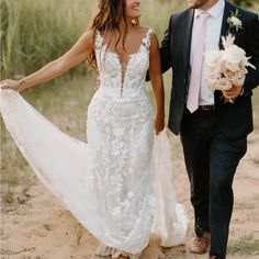 a bride and groom walking together on the beach