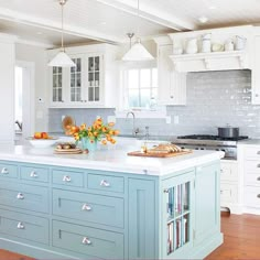 a kitchen with white cabinets and blue island