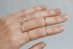 a woman's hand with three gold rings on her left and one in the middle