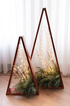 two wooden triangle shaped planters with lights in them