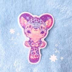 a pink and purple sticker with a cat on it's head sitting on a blue surface