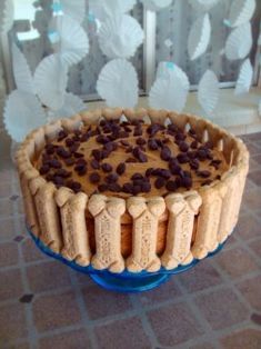 a cake with chocolate chips on top in a blue glass pie dish sitting on a tile floor