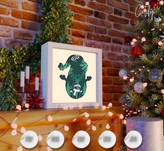 a christmas tree with lights around it and a framed print on the fireplace mantel