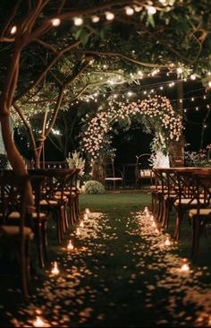 an outdoor wedding venue with candles lit up in the grass and flowers on the ground