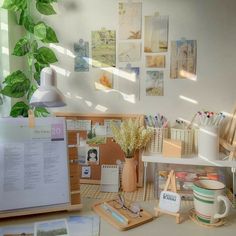 a desk with various office supplies on it and a plant in the corner next to it